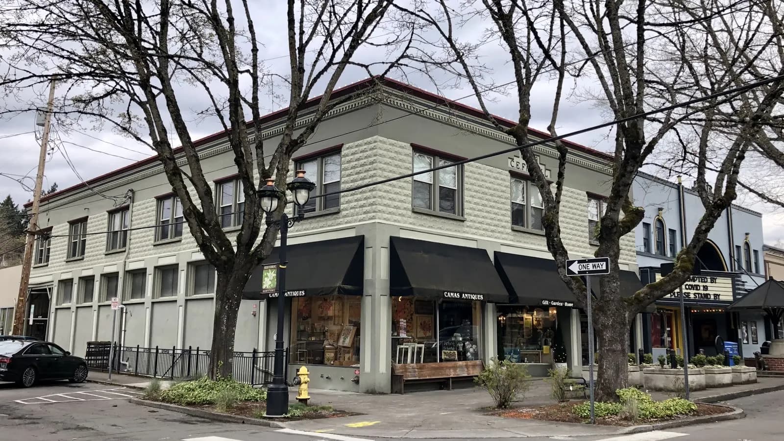 A two-storey corner building in downtown Camas, Washington, with awnings over storefront windows and bare trees along the sidewalk.