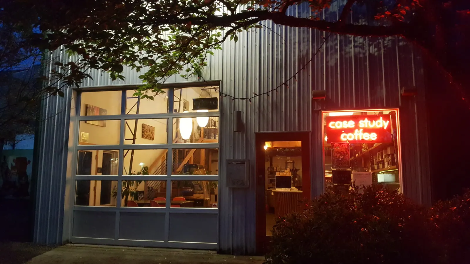 A coffee shop on NE Alberta Street in Portland at night, lit from inside, with a neon sign reading Case Study Coffee.