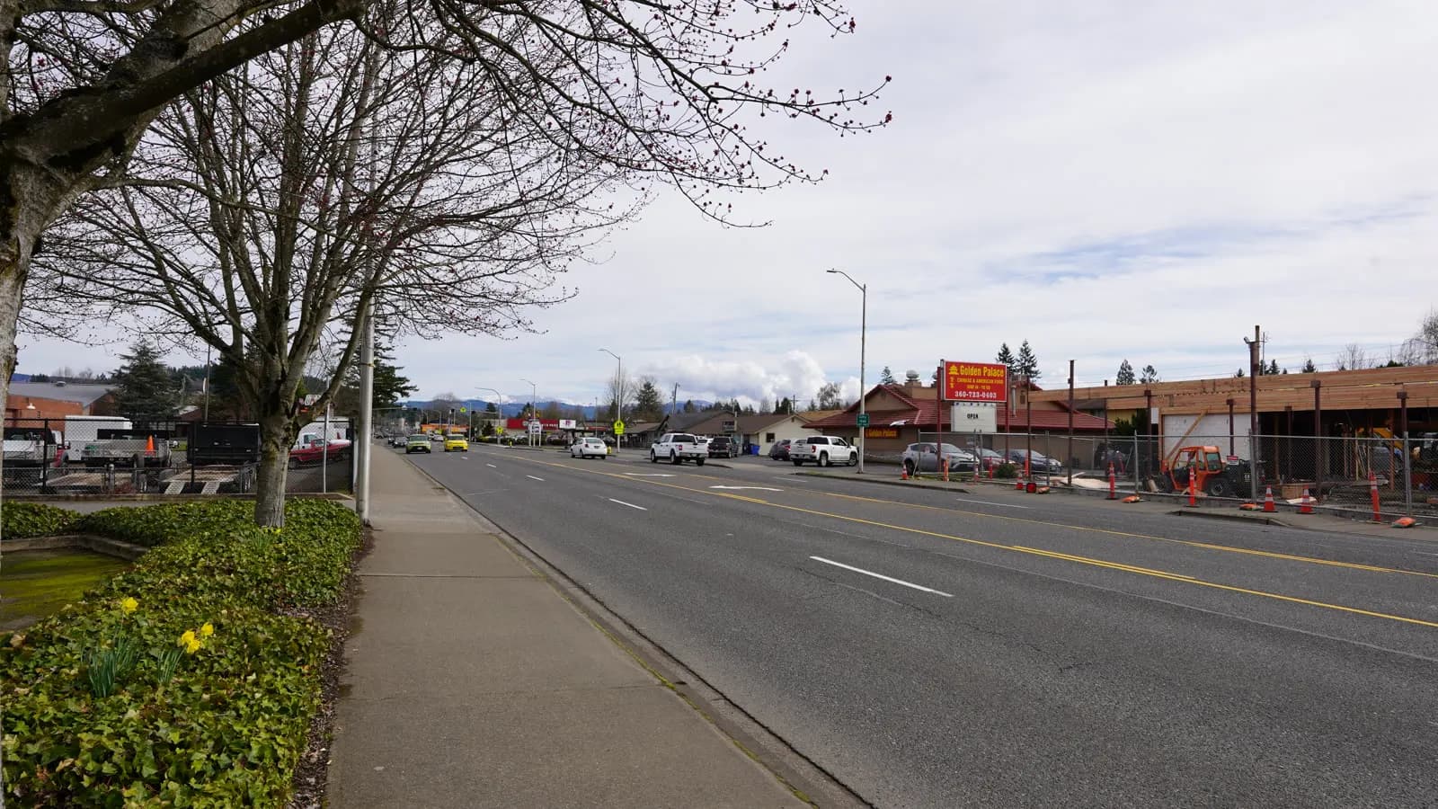 Main Street in Battle Ground, Washington, looking east along a wide road lined with bare trees and low commercial buildings.