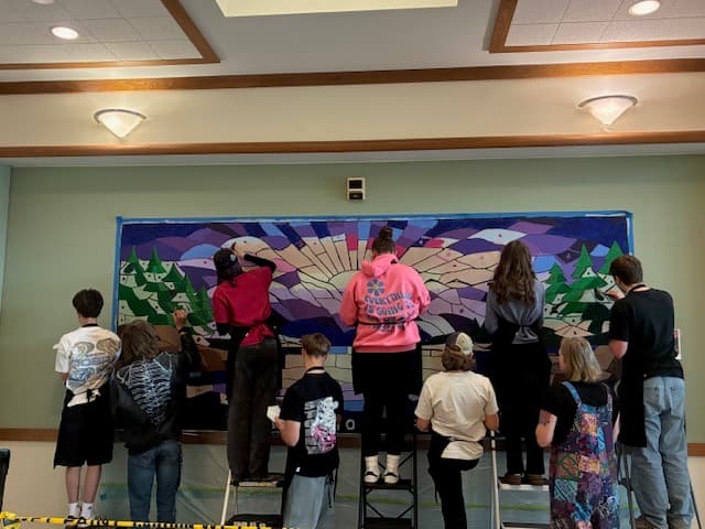 Community volunteers painting a large mural together